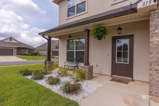 view of exterior entry featuring a yard, stucco siding, and a porch