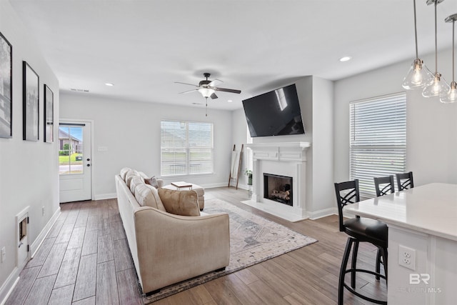 living room featuring recessed lighting, baseboards, ceiling fan, a fireplace with flush hearth, and wood finished floors