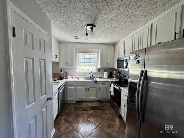 14313 Hemley Rd, Coden, AL 36523 - kitchen with appliances with stainless steel finishes, light countertops, a sink, and a textured ceiling