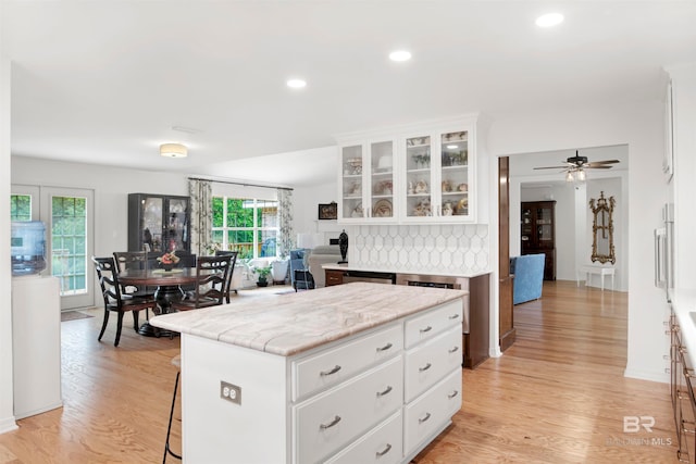 kitchen featuring ceiling fan, a kitchen island, light wood-type flooring, and white cabinetry