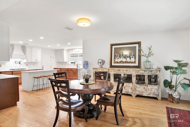 dining space with light wood-type flooring and sink