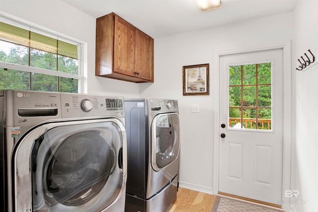 washroom featuring cabinets, independent washer and dryer, and light hardwood / wood-style flooring