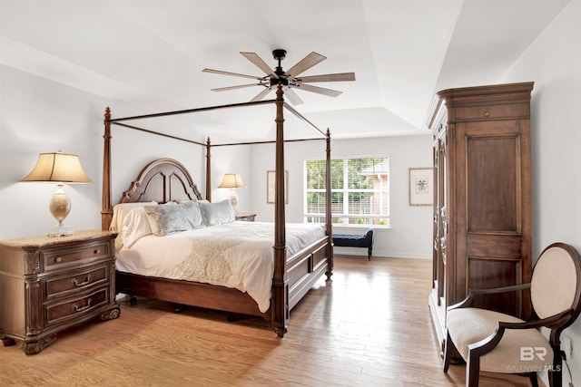 bedroom featuring light hardwood / wood-style floors, ceiling fan, and a tray ceiling