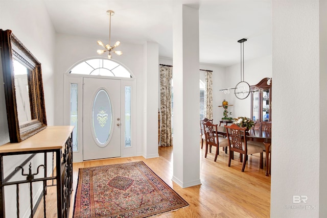 foyer entrance with light hardwood / wood-style flooring and an inviting chandelier