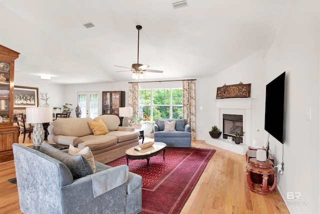 living room featuring light hardwood / wood-style flooring, ceiling fan, and vaulted ceiling