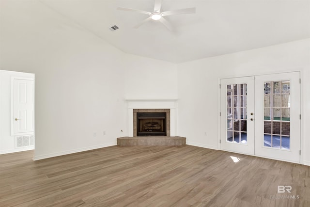 unfurnished living room featuring a fireplace, french doors, ceiling fan, and wood-type flooring