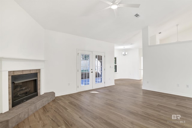 unfurnished living room featuring french doors, ceiling fan with notable chandelier, lofted ceiling, and wood-type flooring