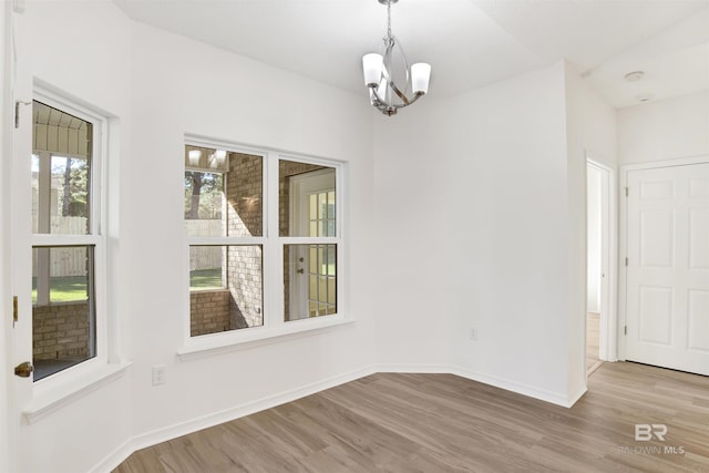 empty room with light hardwood / wood-style flooring and a notable chandelier