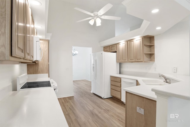 kitchen featuring sink, a high ceiling, light hardwood / wood-style floors, white appliances, and ceiling fan with notable chandelier