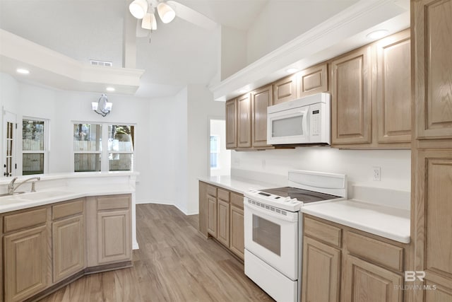 kitchen featuring ceiling fan with notable chandelier, white appliances, sink, light hardwood / wood-style floors, and lofted ceiling