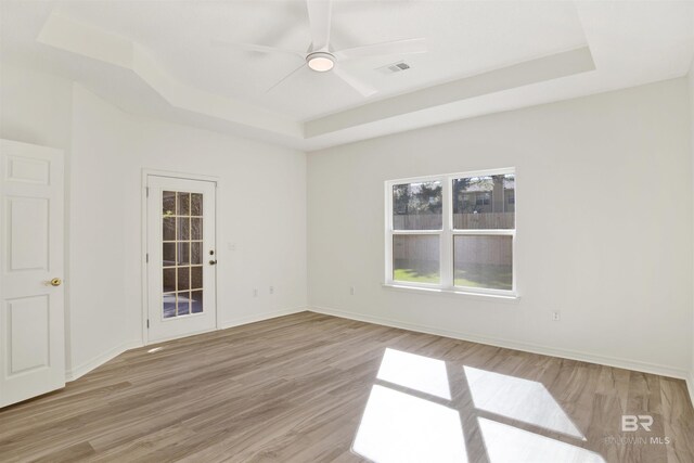 unfurnished room with a tray ceiling, light hardwood / wood-style flooring, and ceiling fan