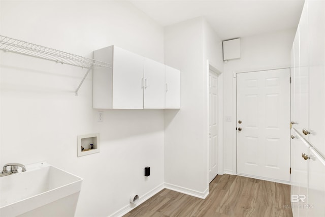 clothes washing area with hookup for a washing machine, sink, cabinets, and light wood-type flooring