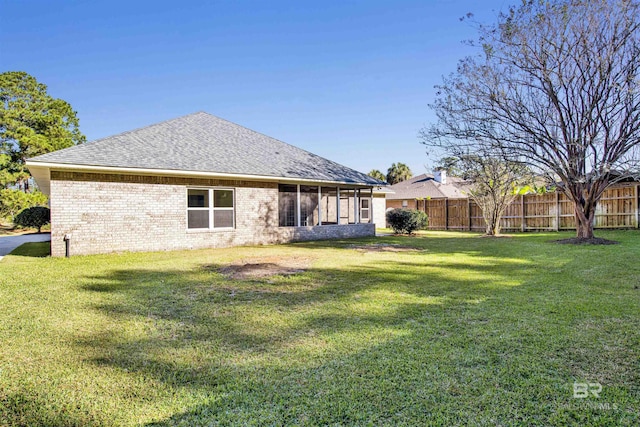 rear view of house with a sunroom and a lawn