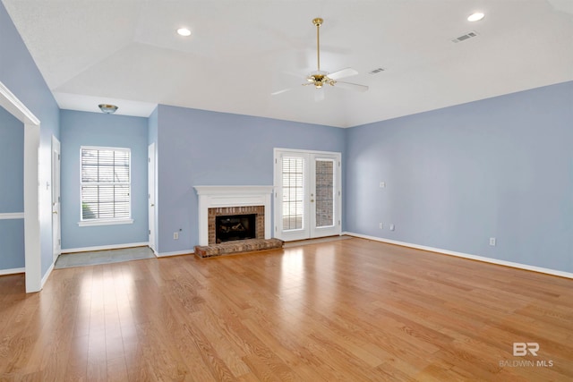 unfurnished living room featuring a brick fireplace, a healthy amount of sunlight, light wood-type flooring, and ceiling fan