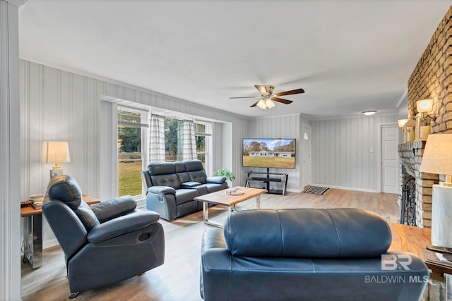 living room with light hardwood / wood-style flooring, a fireplace, ornamental molding, and ceiling fan