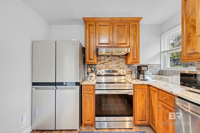 kitchen featuring tasteful backsplash, appliances with stainless steel finishes, and light stone counters