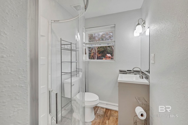 bathroom featuring vanity, a shower with shower door, hardwood / wood-style floors, and toilet