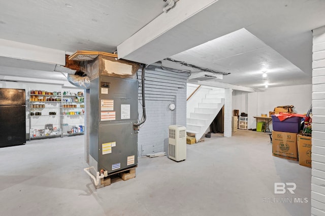 basement featuring black fridge and heating unit