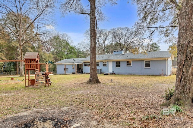 rear view of property featuring a lawn and a playground