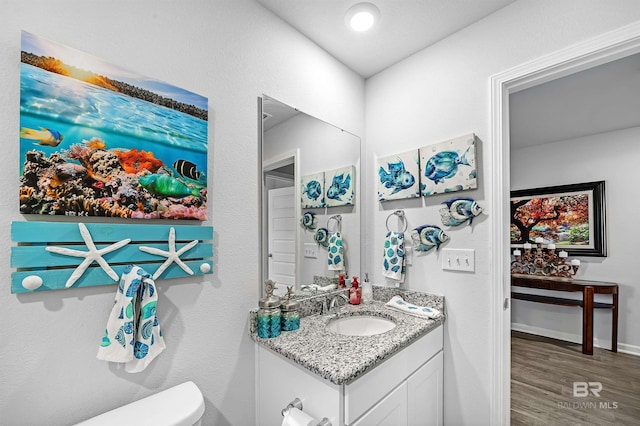 bathroom with hardwood / wood-style flooring, vanity, and toilet