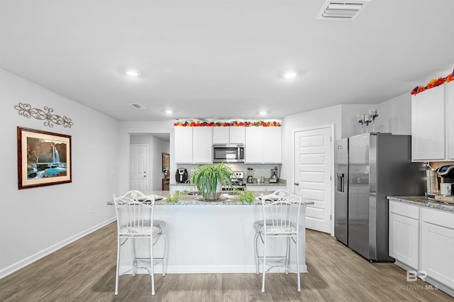 kitchen with light wood-type flooring, a kitchen island, a breakfast bar, and stainless steel appliances