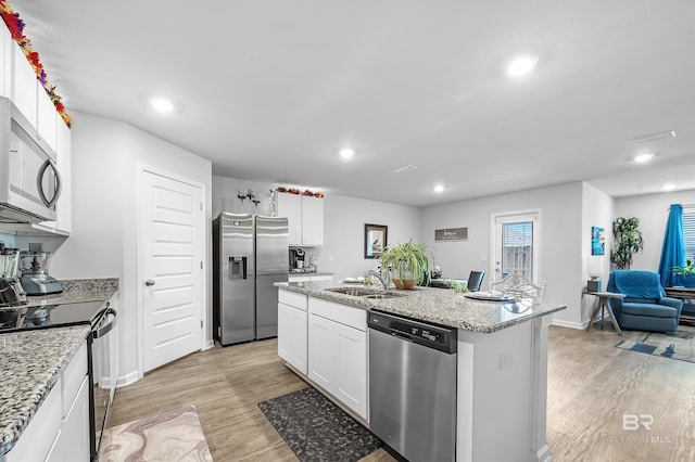 kitchen featuring sink, light wood-type flooring, appliances with stainless steel finishes, an island with sink, and white cabinets