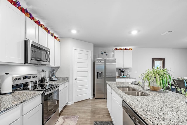 kitchen with stainless steel appliances, light hardwood / wood-style flooring, sink, light stone countertops, and white cabinets