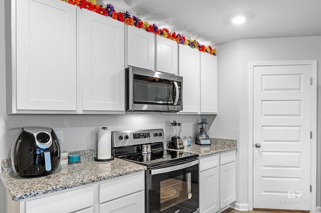 kitchen with appliances with stainless steel finishes, white cabinetry, and light stone countertops