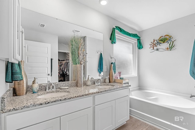 bathroom featuring hardwood / wood-style flooring, a tub, and double vanity