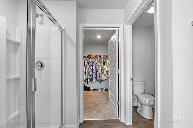 bathroom with toilet, hardwood / wood-style floors, and a shower with shower door