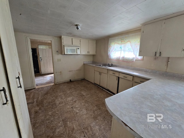 206 E Granberry St, Brewton, AL 36426 - kitchen with light countertops, a sink, white microwave, and cream cabinetry