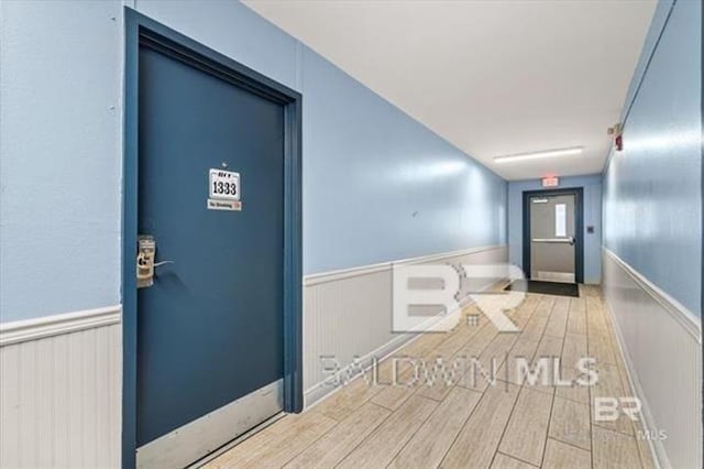 corridor featuring a wainscoted wall and wood tiled floor