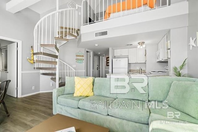 living room featuring stairs, a high ceiling, wood finished floors, and visible vents