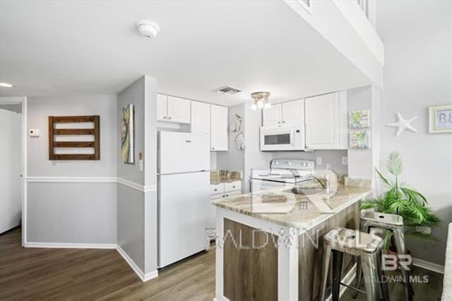 kitchen featuring a peninsula, white appliances, white cabinets, and wood finished floors