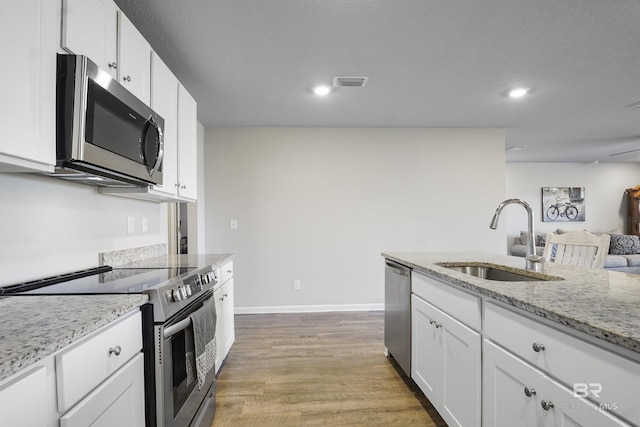 kitchen featuring visible vents, appliances with stainless steel finishes, white cabinets, a sink, and light wood-type flooring