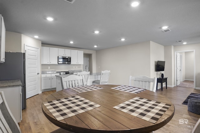 dining room with light wood-type flooring, baseboards, visible vents, and recessed lighting