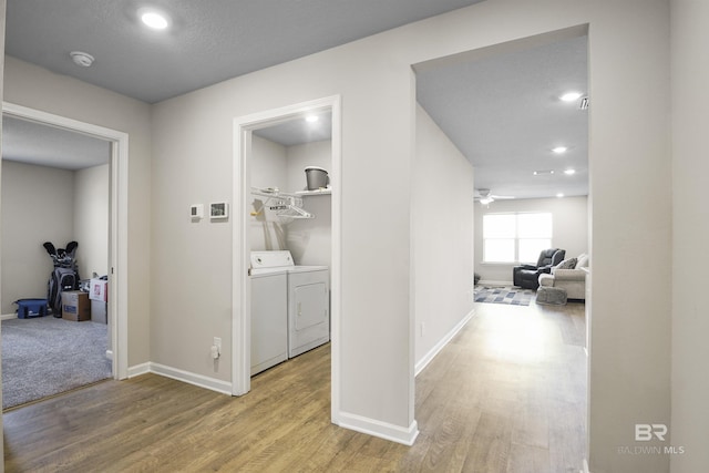 hall with independent washer and dryer, baseboards, and wood finished floors