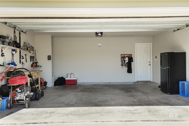 garage with a garage door opener, a workshop area, and freestanding refrigerator