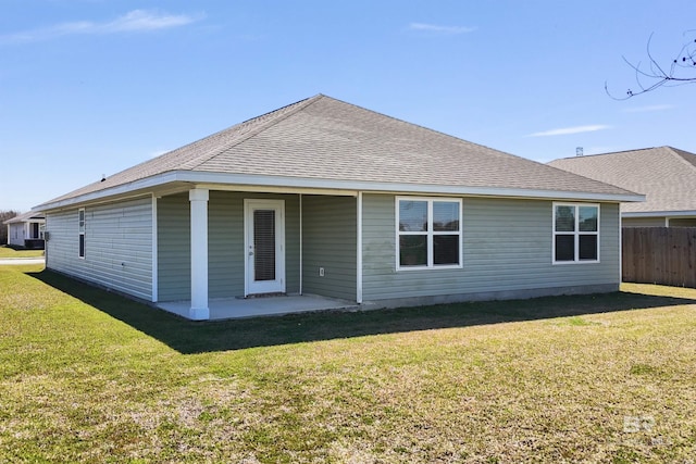 back of house with roof with shingles, a patio area, a lawn, and fence