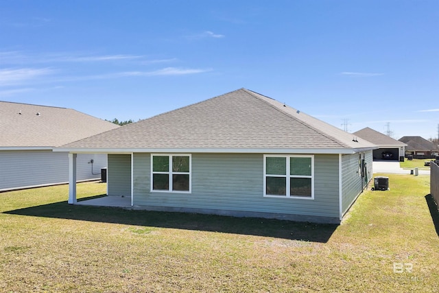 back of house featuring central air condition unit, a lawn, and roof with shingles