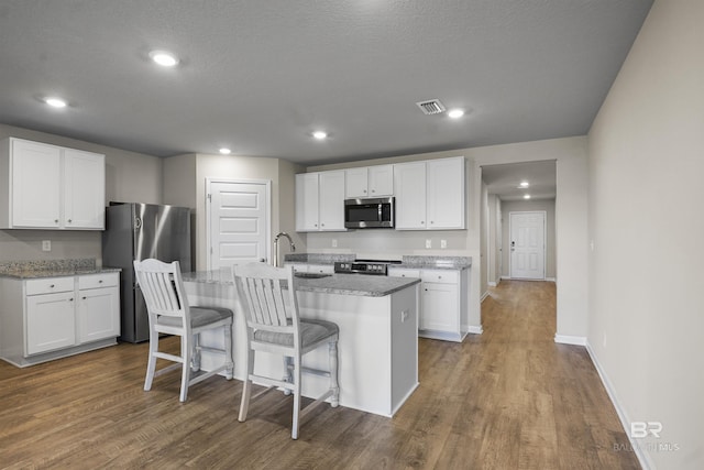 kitchen with appliances with stainless steel finishes, visible vents, and white cabinetry