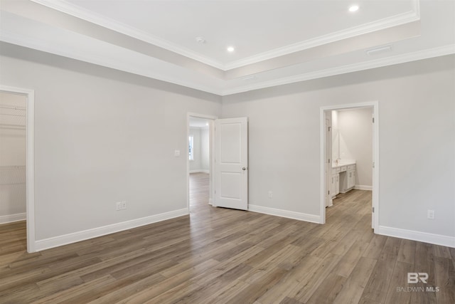 1061 Tampa Ave, Foley, AL 36535 - unfurnished bedroom featuring a spacious closet, wood finished floors, a tray ceiling, crown molding, and baseboards
