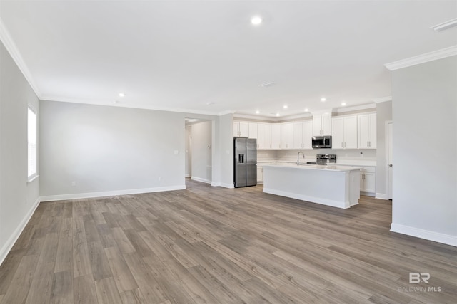 1061 Tampa Ave, Foley, AL 36535 - kitchen with stainless steel appliances, open floor plan, ornamental molding, light countertops, and a center island with sink