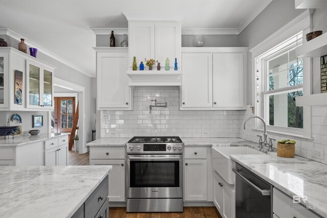 kitchen with a wealth of natural light, white cabinets, appliances with stainless steel finishes, and crown molding