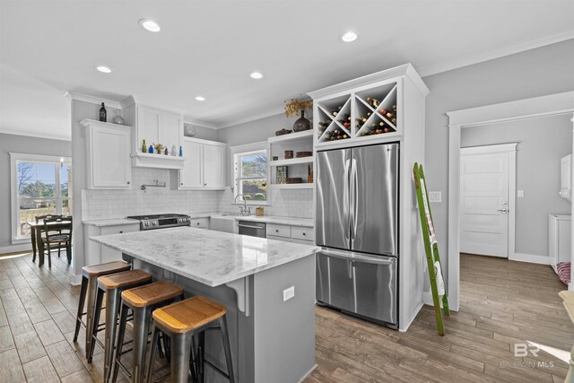 kitchen featuring backsplash, crown molding, wood finished floors, stainless steel appliances, and a sink