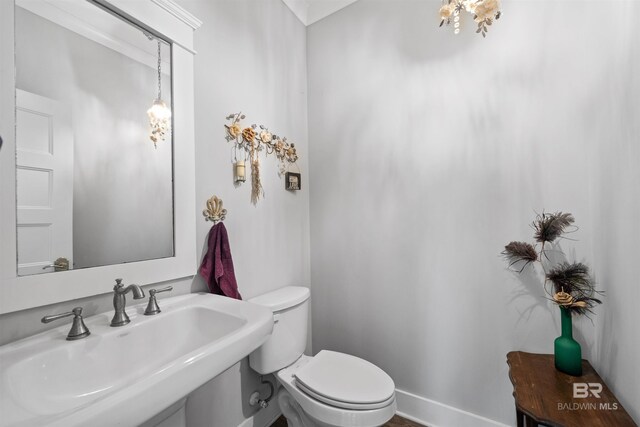 half bathroom featuring toilet, baseboards, and a sink