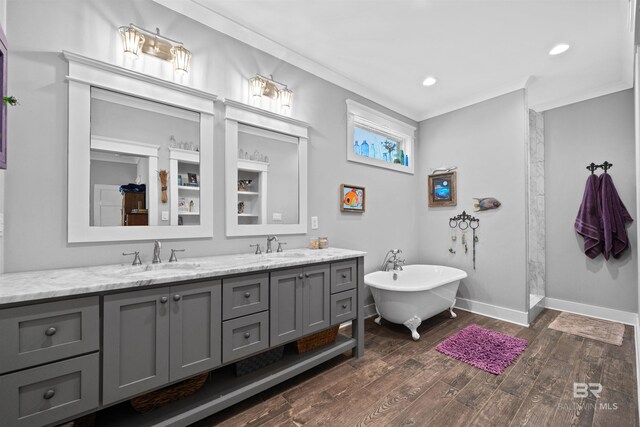 full bath with wood finished floors, baseboards, double vanity, ornamental molding, and a sink