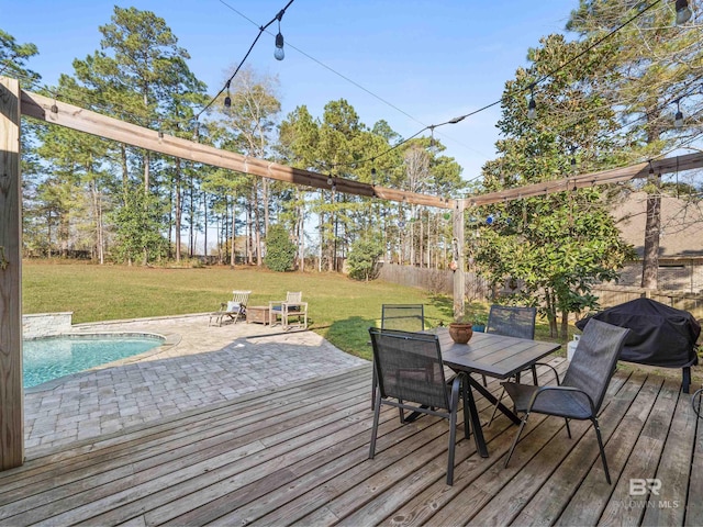 wooden terrace with outdoor dining space, fence, a yard, a grill, and an outdoor pool