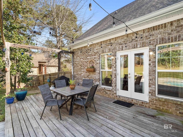 wooden terrace featuring french doors, outdoor dining area, and fence