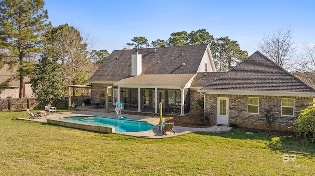 back of property featuring a yard, a sunroom, a fenced in pool, and a patio area